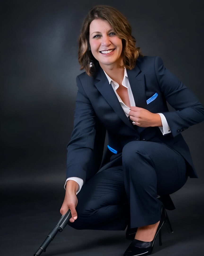 A woman in a suit and tie holding a gun.